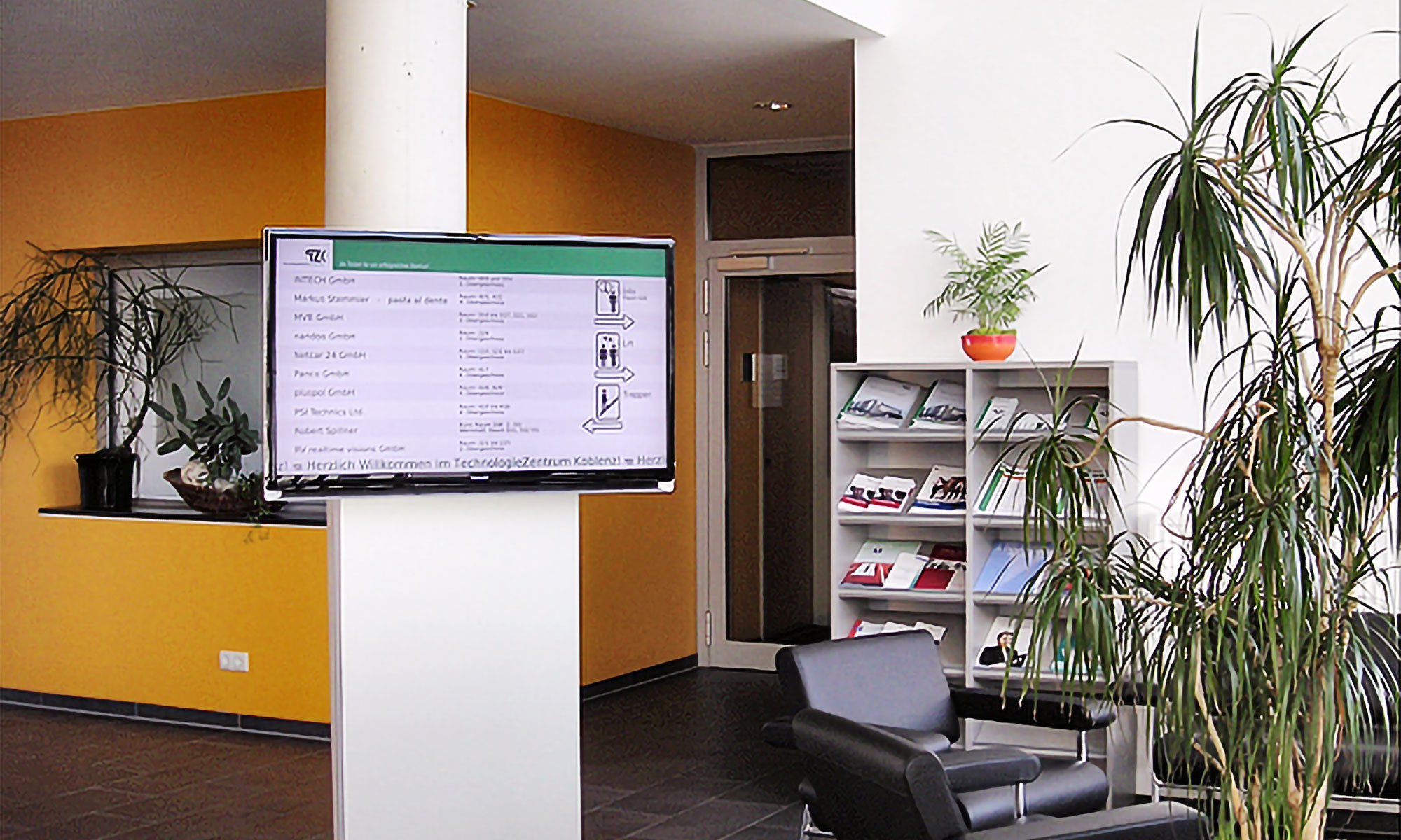 Die Eingangshalle des TechnologieZentrum Koblenz mit einer Displaystele auf der Verschiedene Firmen abgebildet sind