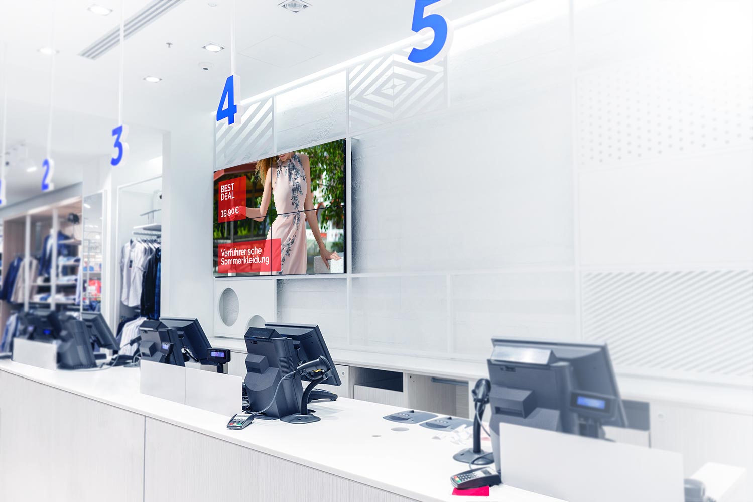 Über einer Gruppe an Kassen hängt eine Displaygruppe mit Werbung für Sommerkleidung in einem Einzelhandel